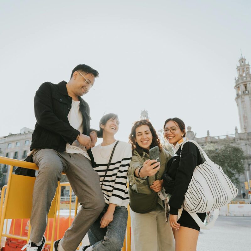Happy group of friends taking a selfie outdoors near historic buildings in Barcelona, Spain.