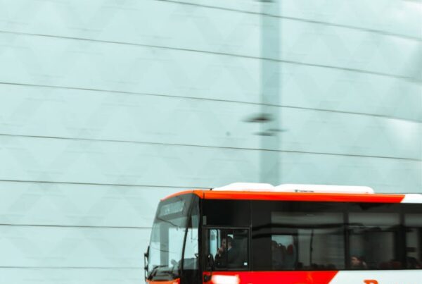 Dynamic cityscape with a red bus in motion, set against a modern building facade.