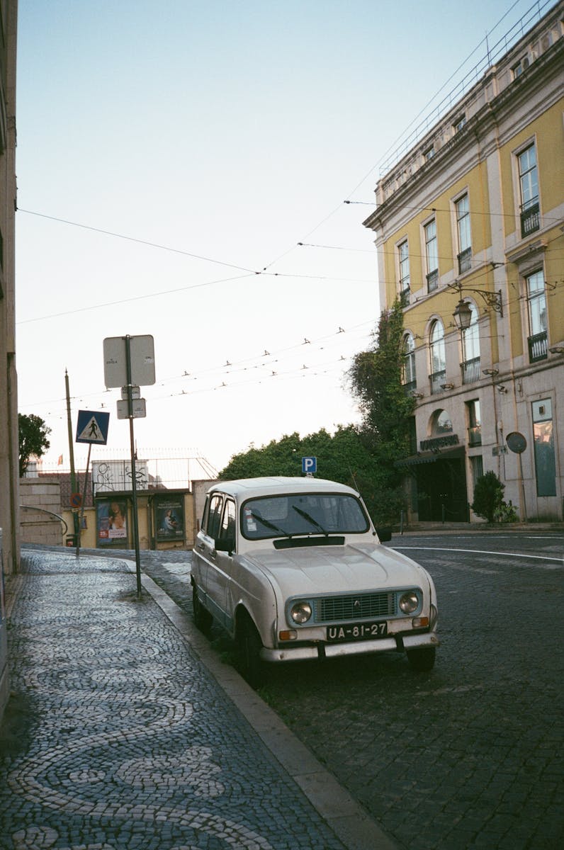 Retro white car parked on picturesque street in Lisbon, showcasing classic European architecture.