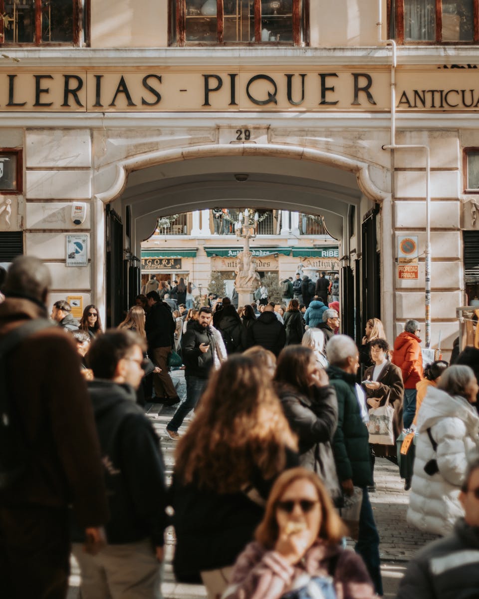 Lively street scene with people walking in front of Galerias Piquer in Madrid, Spain.