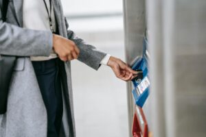 A woman in formal wear using a subway ticket machine, representing urban commuting.