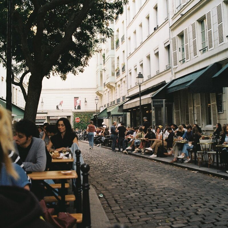 a group of people sitting at tables on a sidewalk
