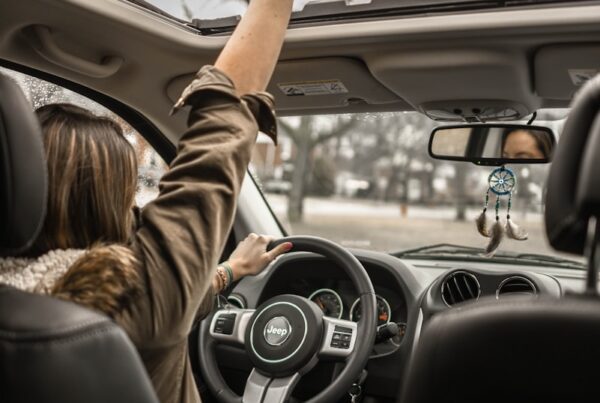 woman raising her right hand inside black and brown vehicle