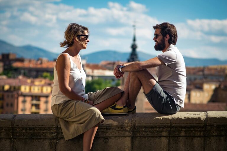 A couple enjoying a sunny day sitting on a ledge in historic Segovia, Spain.