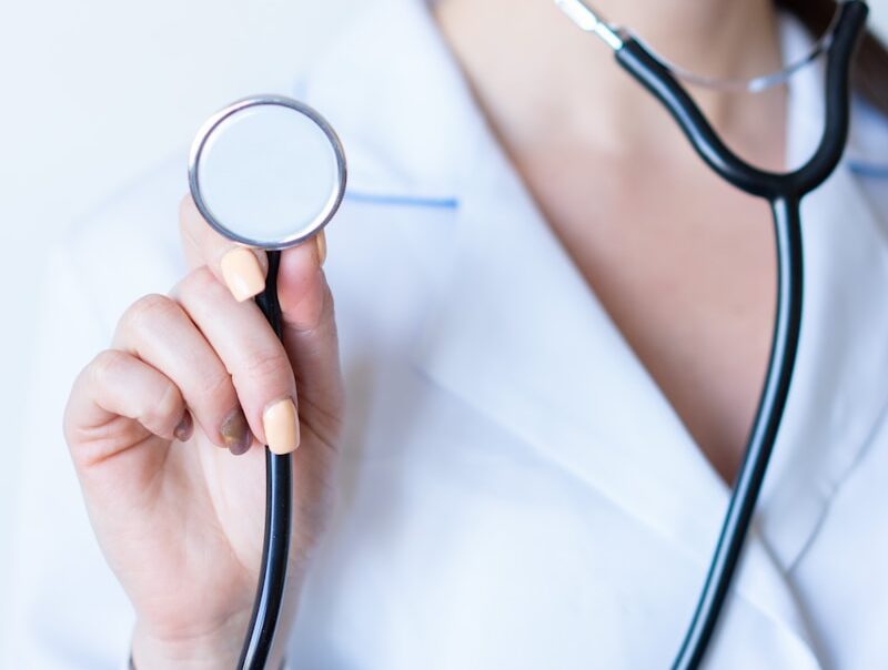 a woman in a white shirt holding a stethoscope